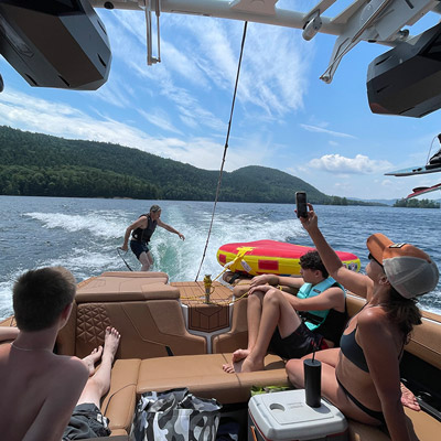 People in boat watching man wakeboarding behind it